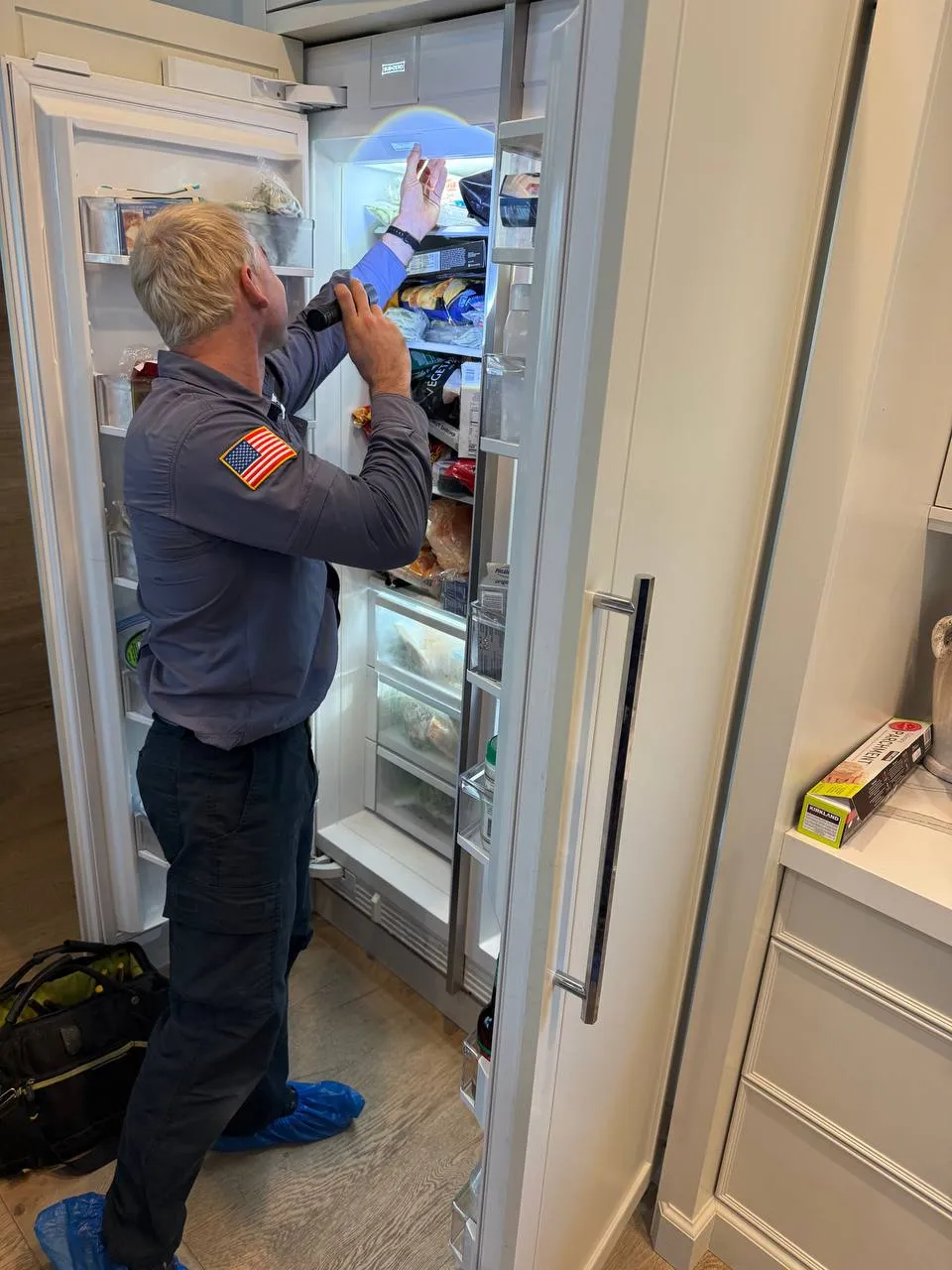 Technician servicing Sub-Zero built-in refrigerator